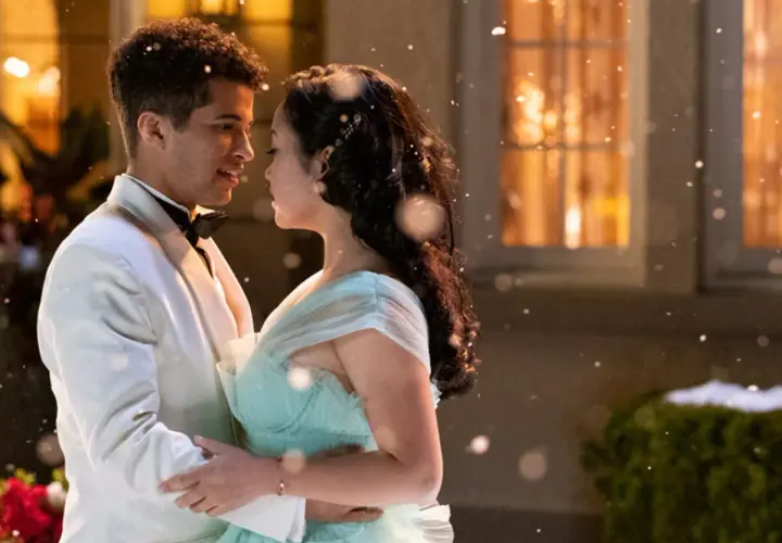 Jordan Fisher dans une scène romantique de films et séries tv. Il danse avec une jeune femme en robe bleu pâle, sous une pluie de flocons.