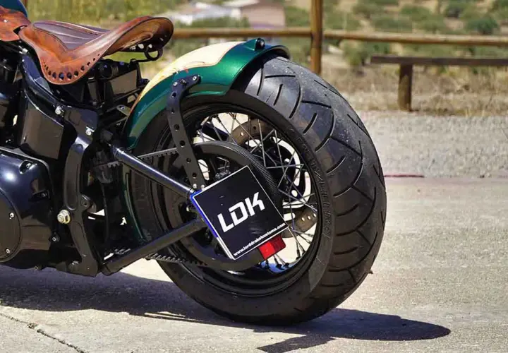 Detalle de moto customizada con asiento de cuero y guardabarros verde. La matrícula, con las medidas adecuadas, muestra el logo LDK.
