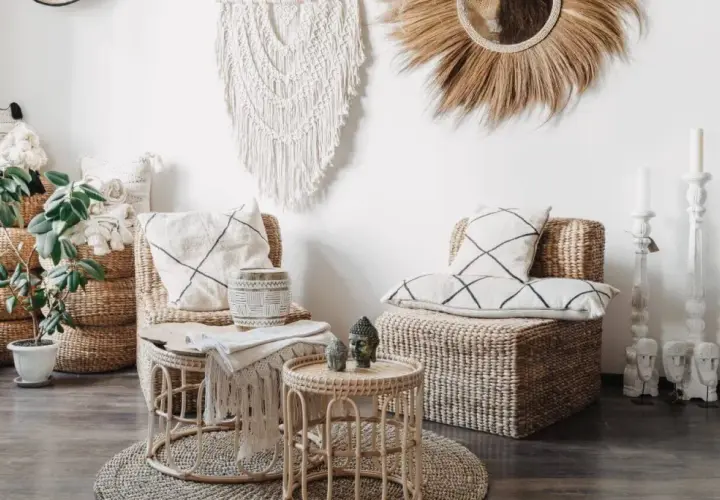 Wnętrze w stylu boho: plecione meble, makrama, lustro z trawy, poduszki z geometrycznymi wzorami i rośliny tworzą przytulną atmosferę.