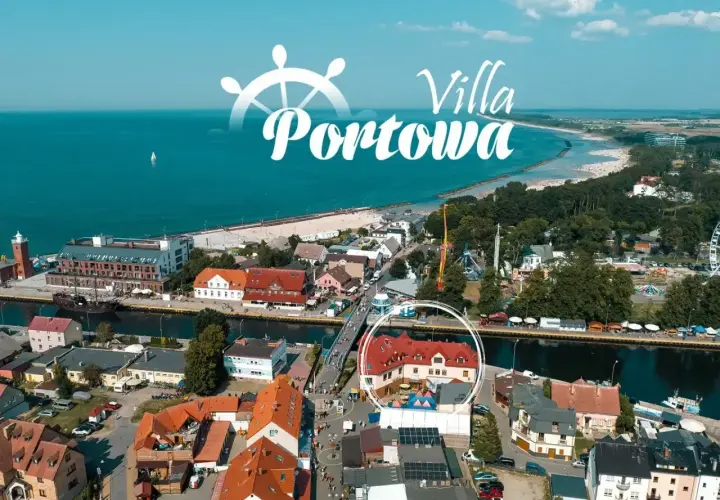 Widok z lotu ptaka na port i plażę w Darłówku. W centrum widoczny budynek z czerwonym dachem, otoczony kołem.