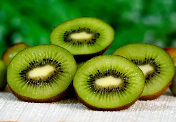 Kiwifruit slices with black seeds. Uważaj na skutki uboczne jedzenia kiwi, jak alergia.