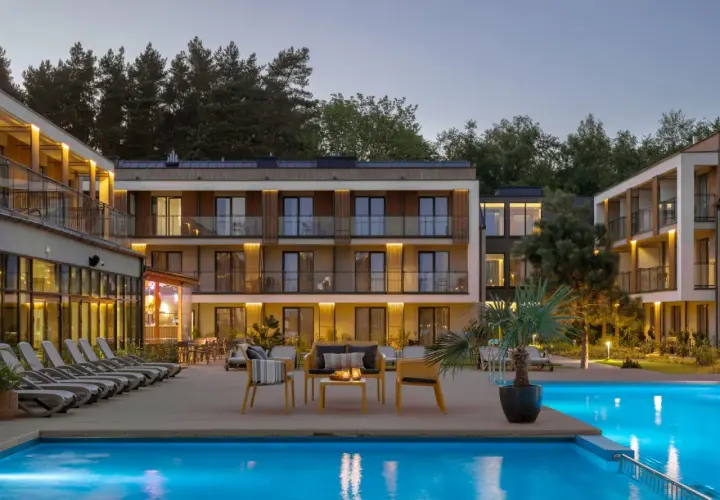 Relaks przy basenie w Saltic Resort & Spa. Nowoczesne budynki, leżaki i palmy tworzą idealne miejsce na wypoczynek.
