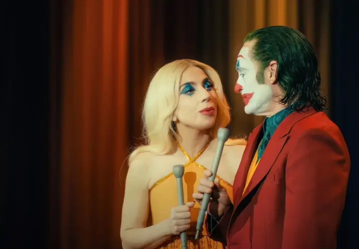 Joker e Harley Quinn, con microfoni in mano, si guardano intensamente. La trama del film si infittisce.