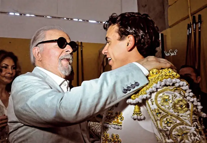 Un hombre mayor con gafas de sol abraza al torero Juan de Castilla, quien luce su traje de luces.