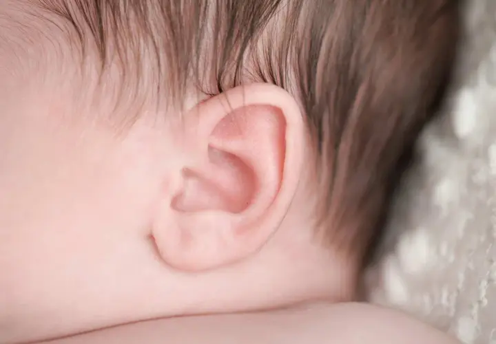Primo piano dell'orecchio di un neonato, un dettaglio delicato che può essere interessato da otite nei bambini.