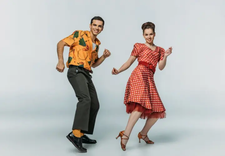 Coppia in abiti vintage che esegue boogie woogie passi e figure con gioia.