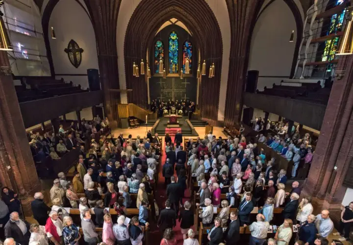 Menschen versammeln sich in einer Kirche für einen evangelischen Gottesdienst. Die evang. Gottesdienstordnung wird vorbereitet.