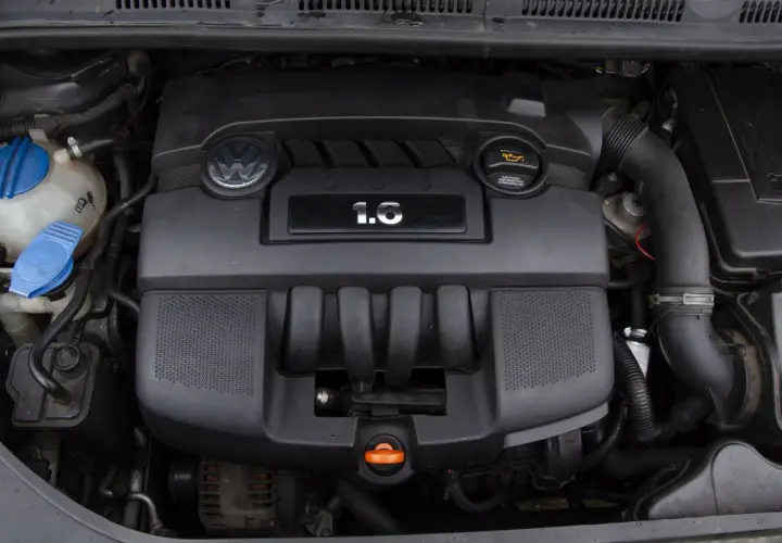 Silnik Volkswagena z oznaczeniem 1.6 MPI. Widoczny jest czarny plastikowy kolektor, logo VW i zbiornik płynu chłodniczego.
