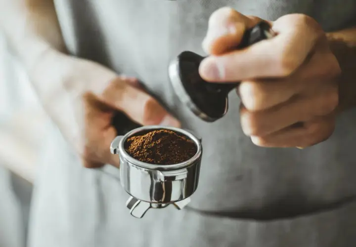 Barista tamped den frisch gemahlenen Kaffee für einen perfekten Kaffee shot.