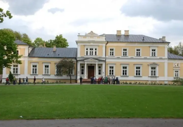 Pałac w Ciechanowcu, jedna z atrakcji regionu, otoczony zielenią. Grupa osób zwiedza teren.