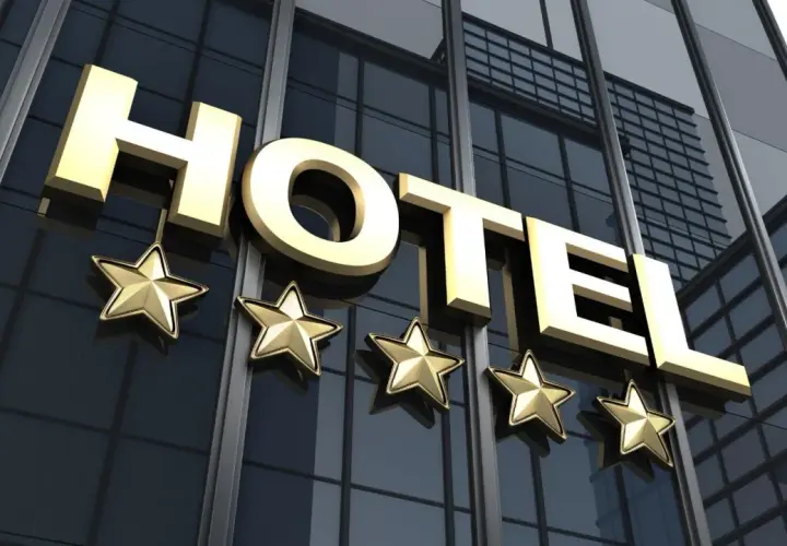 Złoty napis HOTEL i pięć gwiazdek na nowoczesnym, szklanym budynku. To zapowiedź luksusowego hotelu.