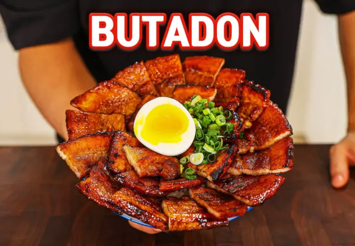 A generous serving of glistening pork donburi, topped with a perfectly soft-boiled egg and chopped green onions.