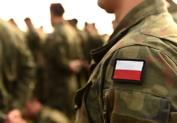 Żołnierz w mundurze polowym z naszywką flagi Polski. Weteran dumny ze swojej służby.