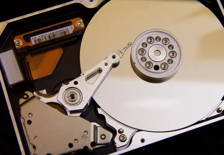 Vue rapprochée de l'intérieur d'un disque dur de PC, montrant le plateau, la tête de lecture/écriture et le moteur. L'emplacement du disque dur PC est essentiel pour le stockage des données.