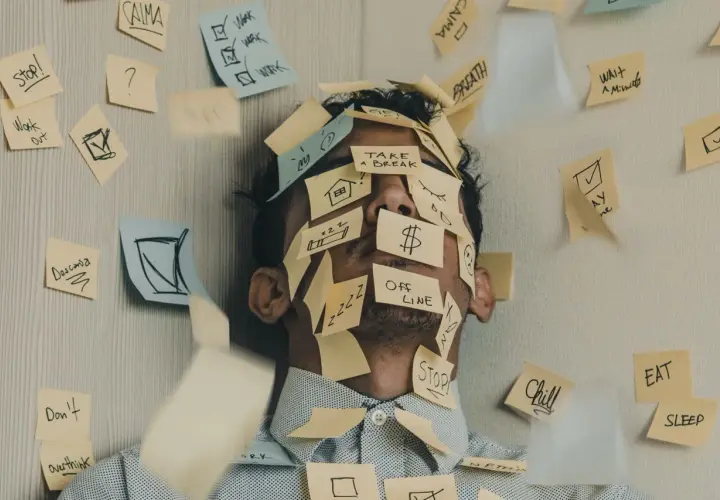 Twarz mężczyzny zasłonięta karteczkami z przypomnieniami: "Stop!", "Work", "Take a break", "Offline". To chyba właśnie jest presja, co to znaczy?