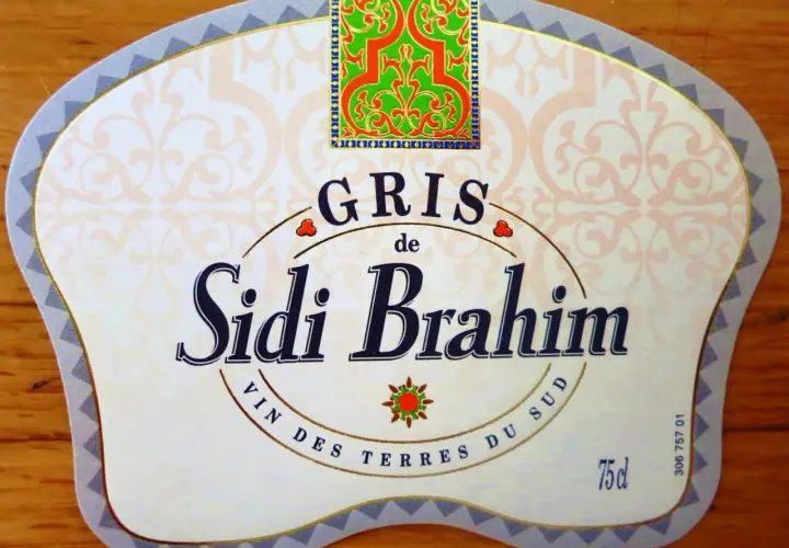 Étiquette de vin Sidi Brahim Gris, avec un motif floral vert et rouge en haut. Le texte "Sidi Brahim" est en gros caractères bleus.
