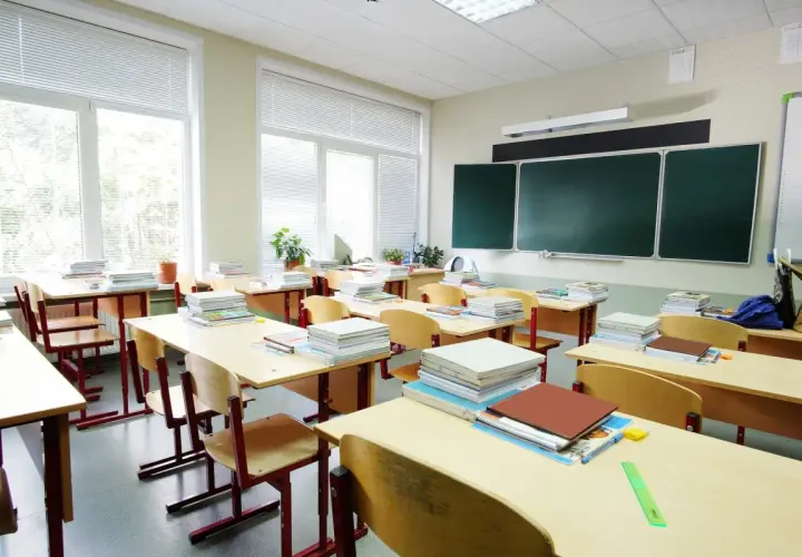 Puste ławki i stosy książek w sali lekcyjnej, jakby właśnie skończył się rok szkolny.