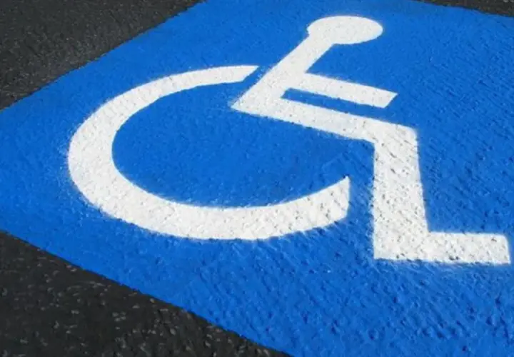 Niebieskie pole z białym symbolem wózka inwalidzkiego. Czy parking dla niepełnosprawnych jest płatny?
