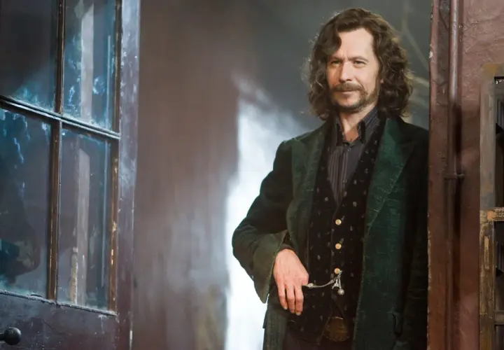 Gary Oldman jako Syriusz Black w Harry Potterze, stojący obok drzwi z szybą.