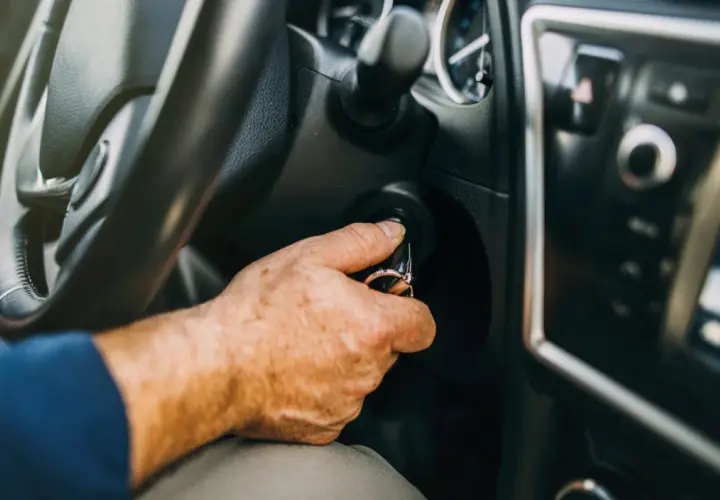 Mano insertando llave en el encendido. Al poner en marcha un motor de gasolina es conveniente tener el coche listo.