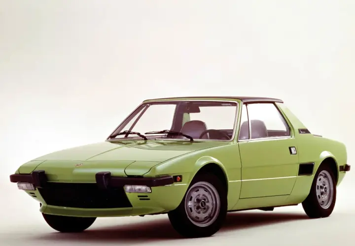 Zielony Fiat X1/9 z czarnym dachem, sportowy samochód z lat 70. na białym tle.