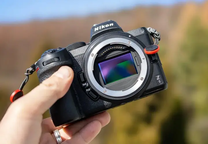 Dłoń trzyma aparat Nikon Z5 z widocznym sensorem, gotowy do testów w plenerze.