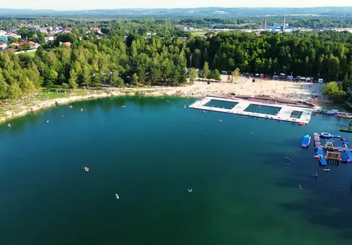 Letni dzień nad wodą w Trzebini. Ludzie odpoczywają na plaży i pływają w jeziorze, które przypomina Balaton.