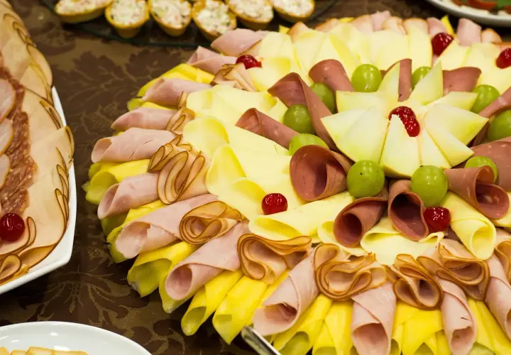 Un buffet froid facile et pas cher : plateau de charcuterie, fromages roulés, raisins verts et cerises confites.