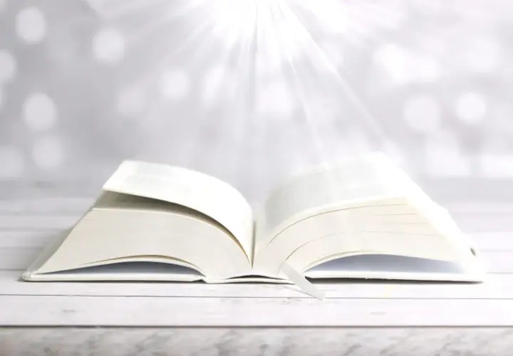Ein aufgeschlagenes Buch mit einem Lesezeichen, das Lichtstrahlen empfängt. Wie in Phlm 1:3, ein Symbol für Hoffnung und Weisheit.