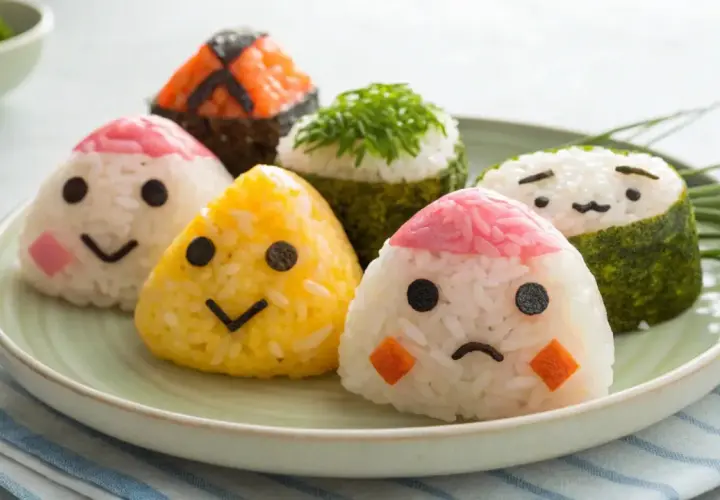 Cute onigiri with faces on a plate. If your onigiri falls apart, try using stickier rice and pressing it firmly.