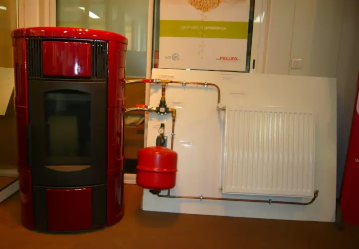 Poêle à granulé hydro rouge connecté à un radiateur blanc. Le système de chauffage est prêt.