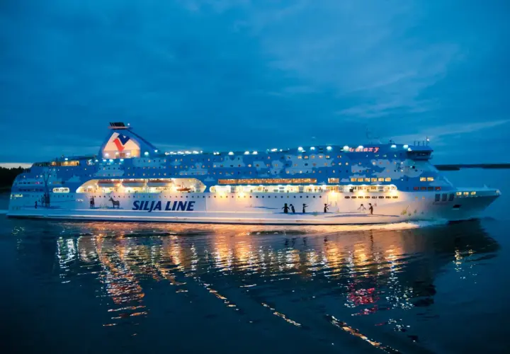 Prom Silja Line Galaxy płynie po wodzie o zmierzchu, odbijając światła w mroku. Podróż z Rygi do Helsinek zaczyna się!