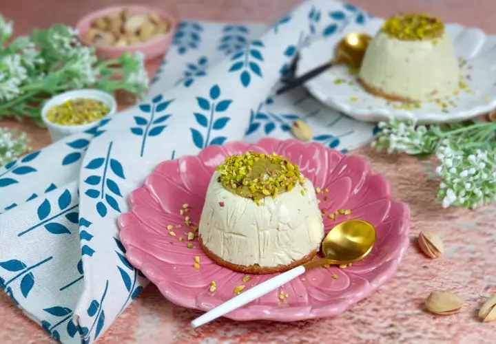 Delizioso semifreddo al pistacchio, guarnito con granella e crema di pistacchi, servito su un piatto rosa.