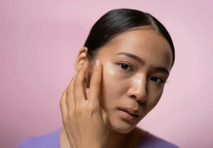 En kvinna applicerar en kräm i ansiktet, kanske en retinolkräm för ett strålande retinol ansikte.