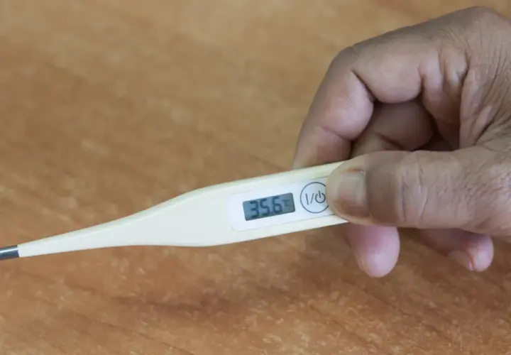 Dłoń trzyma termometr pokazujący 35.6°C. To niska temperatura u dorosłego.