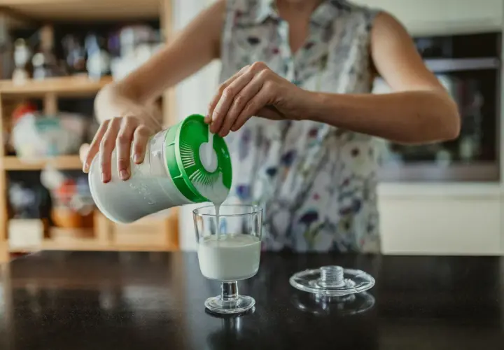 Persona sirve kéfir en un vaso. ¿Cuándo tomar kéfir antes o después de las comidas?