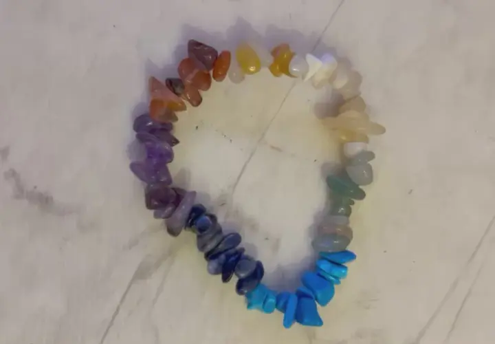 Ett färgglatt chakraarmband med stenar i regnbågens färger, från rött till lila.