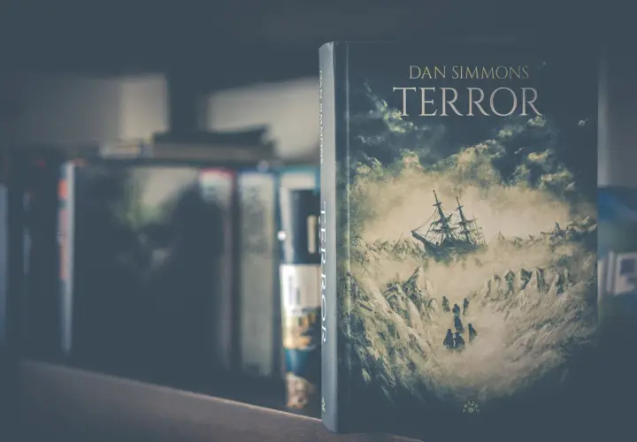 Okładka książki "Terror" Dana Simmonsa przedstawia żaglowiec walczący z lodowymi górami i sztormem.