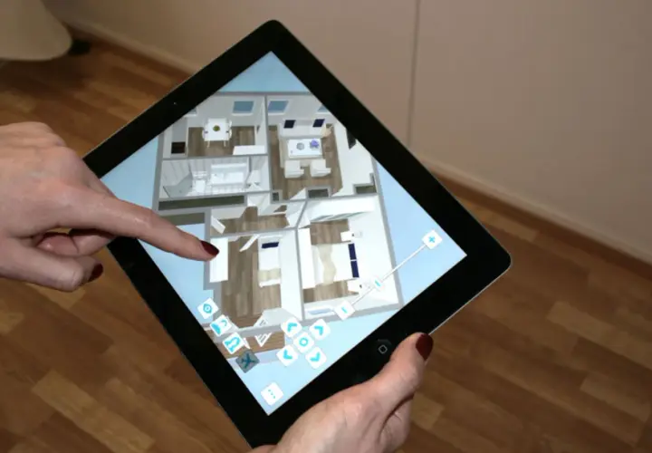 Mit einem Tablet wird die Planung zum Haus einrichten. Eine Person navigiert durch einen 3D-Grundriss, um Möbel zu platzieren und Räume zu gestalten.