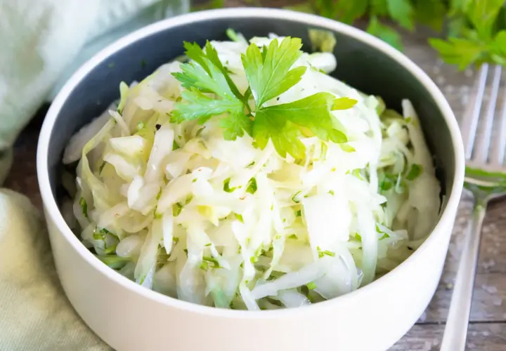 Frischer Krautsalat, perfekt zum krautsalat selber machen. Mit Petersilie garniert, serviert in einer Schüssel.