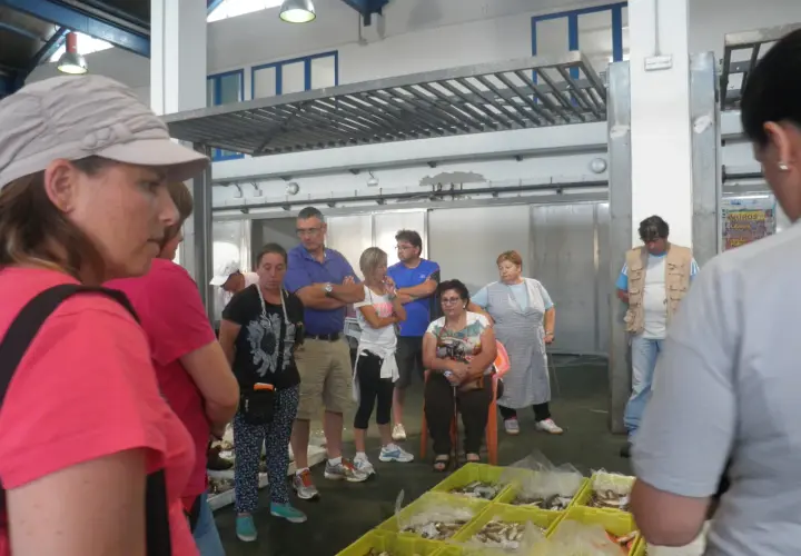 Gente en un mercado, con una lonja de muros al fondo.