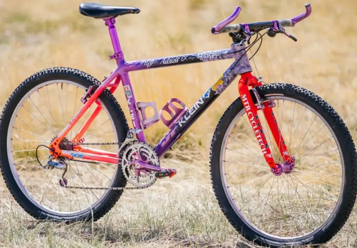 A vibrant Klein Adroit mountain bike with purple and orange fade paint, ready for an adventure.