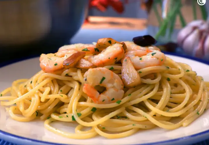 Espaguetis al ajillo con gambas, ajo laminado y perejil picado, servidos en un plato blanco.