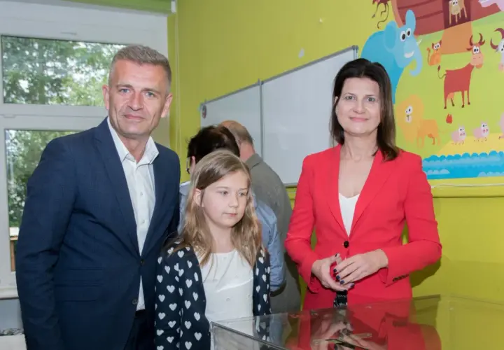 Bartosz Arłukowicz z córką i koleżanką na tle kolorowej ściany z bajkowymi zwierzątkami.