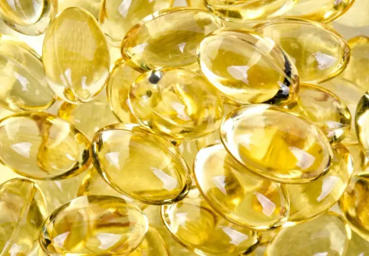 En närbild av genomskinliga, ovala kapslar fyllda med gyllene olja, som påminner om d vitamin-tillskott.