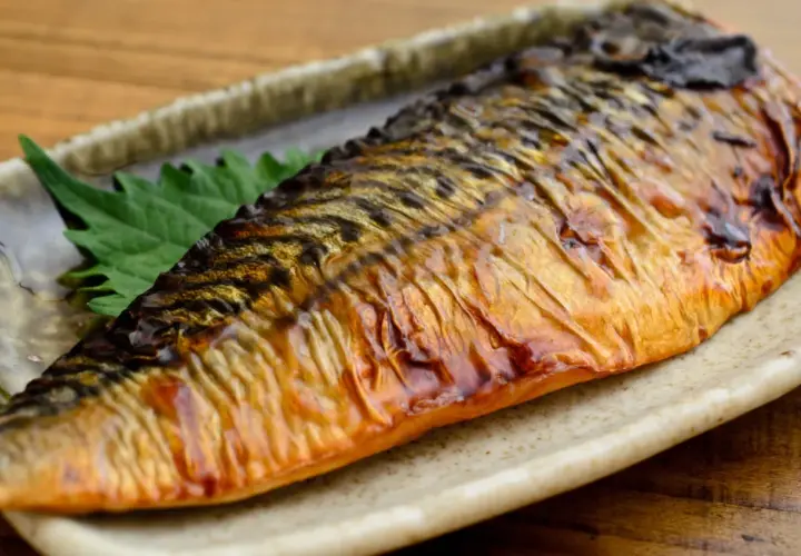 Pieczona makrela na talerzu, z zielonym liściem. Czy makrela jest zdrowa? Tak, to bogactwo kwasów omega-3!