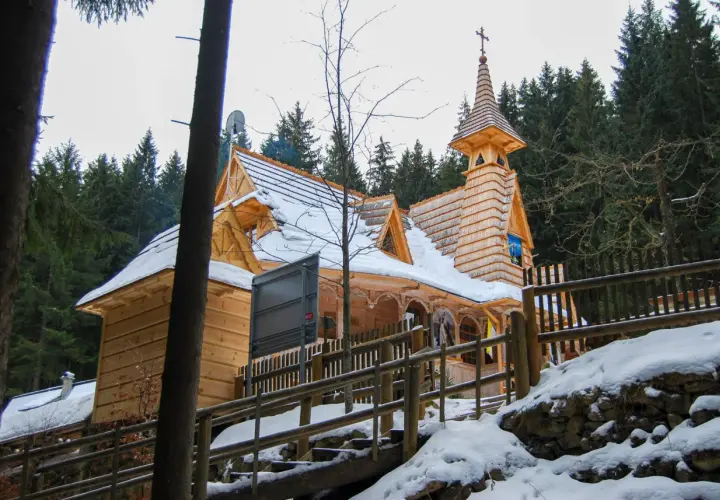Drewniane sanktuarium maryjne na Wiktorówkach w zimowej scenerii, otoczone lasem iglastym.