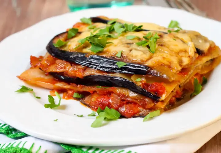 Deliciosa lasaña de berenjena, capas de berenjena, salsa de tomate y queso fundido, espolvoreada con perejil fresco.
