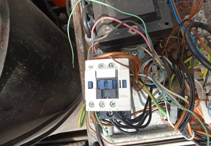 Widok z bliska na wyłącznik silnikowy Schneider z licznymi przewodami w skrzynce elektrycznej.