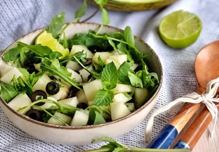 Refrescante ensalada de melón con rúcula, aceitunas negras y menta. Un toque de lima realza su sabor.